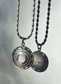 Sterling silver pendant with clear quartz crystal and sacred geometry design casting a shadow on white background
