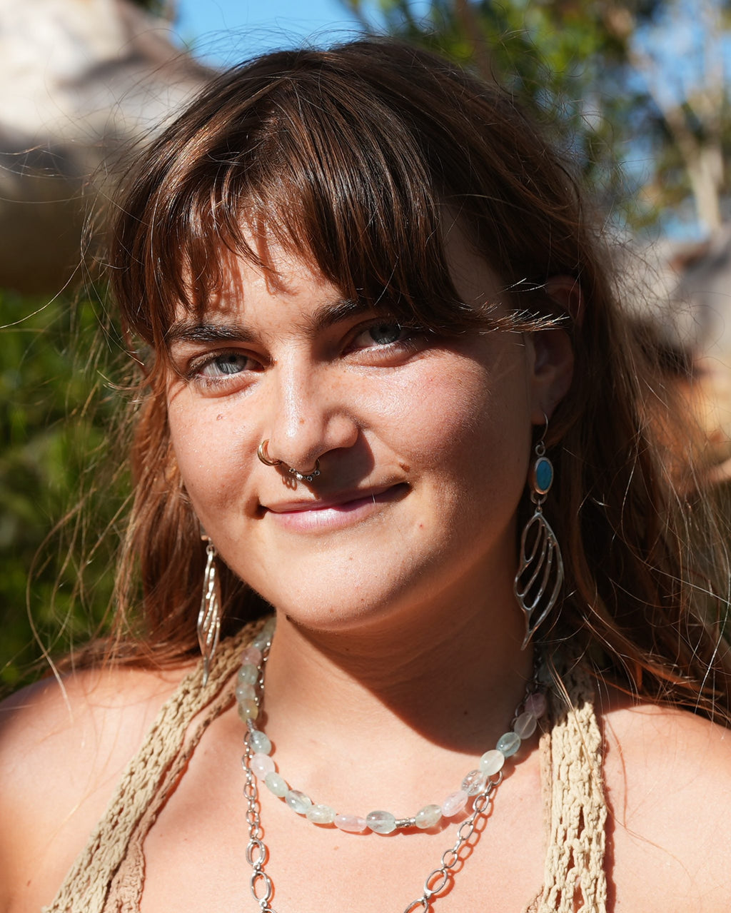 Model wearing the ethereal turquoise wing earrings to show the length and nature-inspired style