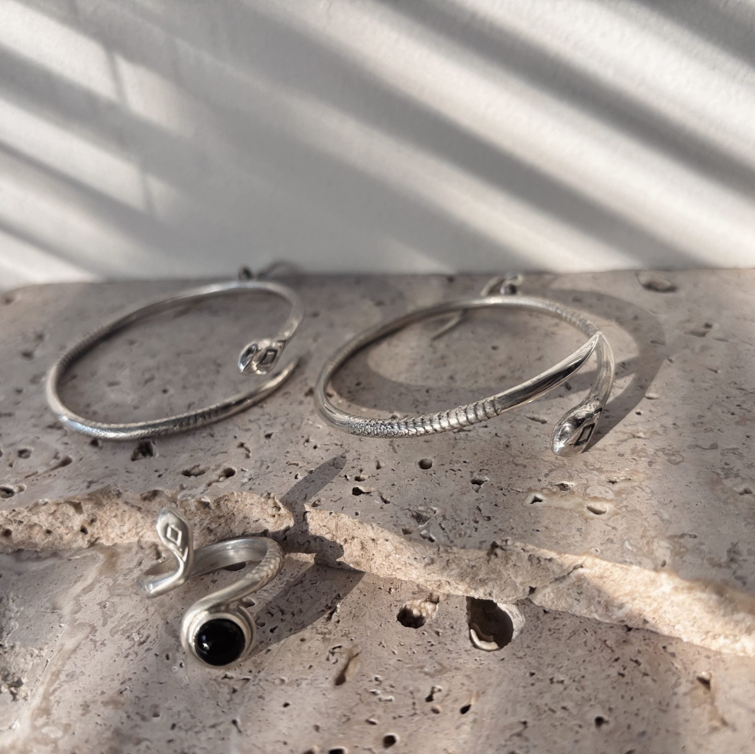 Close-up of the sleek, polished finish and fluid shape of the silver snake earrings